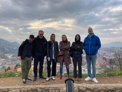 A tour group posing above Sarajevo under dramatic clouds
