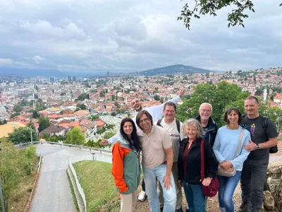 A tour group posing at a cloudy Sarajevo viewpoint
