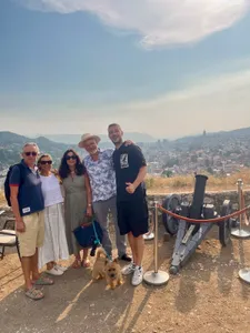 A tour group posing beside a cannon overlooking Sarajevo