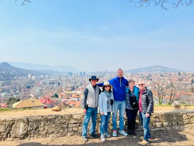 A tour guide and visitors overlooking Sarajevo
