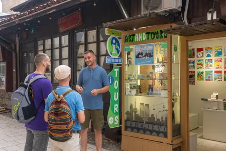 A tour guide welcoming visitors at the Art and Tours booth in Sarajevo