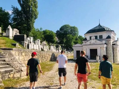 Four visitors walking through a historic Sarajevo cemetery